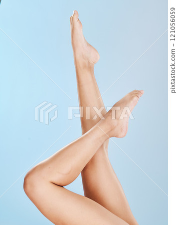 Closeup of unknown woman posing with her soft skin on her legs against a blue studio background. One female only feeling confident while showing her hairless, smooth legs after waxing or epilation 121056059