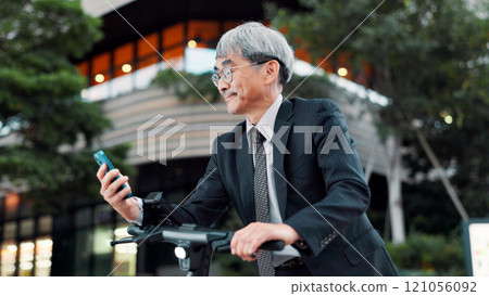 Businessman, phone or electrical scooter in city for travel, clean or sustainable transport. Commute ride, mature or eco friendly bike with mobile app technology for location or map in Japan Businessman, phone or electrical scooter in city for travel, clean or sustainable transport. Commute ride, mature or eco friendly bike with mobile app technology for location or map in Japan 121056092