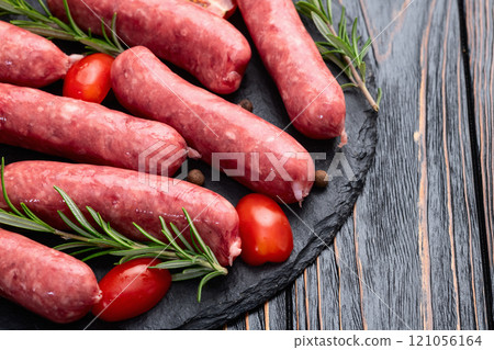 Raw beef sausages with rosemary and tomatoes photography . Top view 121056164