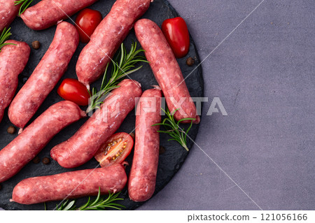 Raw beef sausages with rosemary and tomatoes photography . Top view 121056166