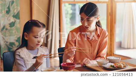 Mom, girl and chopsticks at lunch, home or teaching for food, eating or bonding for love in dining room. People, mother and daughter family house for meal, diet or nutrition with learning in Japan Mom, girl and chopsticks at lunch, home or teaching for food, eating or bonding for love in dining room. People, mother and daughter family house for meal, diet or nutrition with learning in Japan 121056413