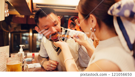 Woman, feeding and man for romantic dinner, meal or anniversary in restaurant for Asian food in city. Couple, eating and bonding together with holiday, vacation and help for tourism or night in Japan 121056650