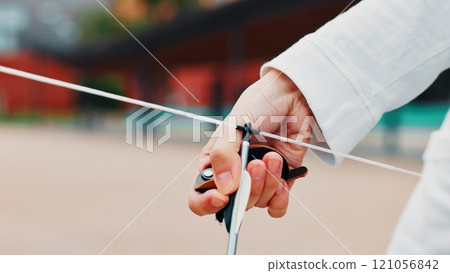 Archery, person and hands with arrow, bow or string for aim, skill or talent in preparation for precision or hunting in city. Japan, closeup or professional archer with weapon for sport or combat 121056842