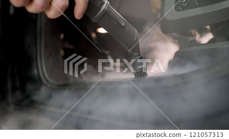 Steam car interior cleaning. Car wash, a worker cleans the thresholds of the car with a steam cleaner. Car interior cleaning. Steam car interior cleaning. Car wash, a worker cleans the thresholds of the car with a steam cleaner. Car interior cleaning. 121057313
