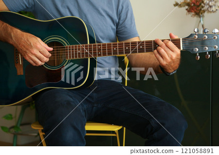 Close-up of a man's hands playing an G chord on acoustic guitar at home 121058891