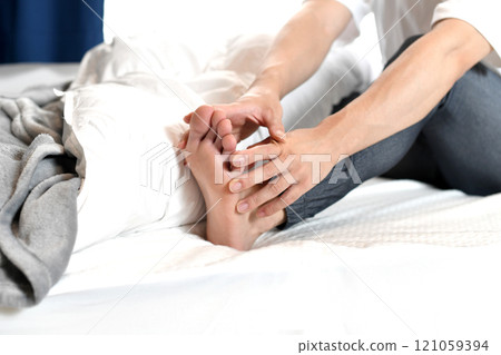 Asian man's feet suffering from leg pain on the bed Asian man's feet suffering from leg pain on the bed 121059394