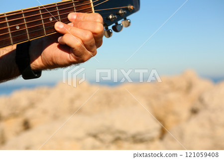 Close-up of a man playing the D chord on an acoustic guitar 121059408