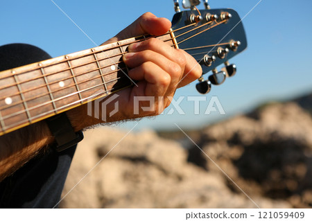 Close-up of a man playing the E chord on an acoustic guitar Close-up of a man playing the E chord on an acoustic guitar 121059409