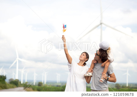 Happiness family walking wind turbine farm while father piggyback of daughter together. Happiness family walking wind turbine farm while father piggyback of daughter together. 121059678