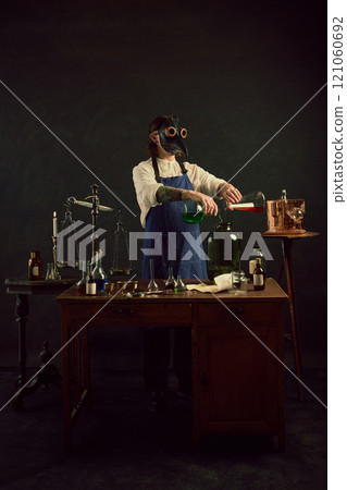 Alchemist pours bright green liquid, evoking distillation or alcohol making in vintage laboratory against dark mystery background. Alchemist pours bright green liquid, evoking distillation or alcohol making in vintage laboratory against dark mystery background. 121060692
