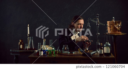 Young man, dressed vintage costume sitting in vintage laboratory and study of ancient remedies against dark mystery background. Young man, dressed vintage costume sitting in vintage laboratory and study of ancient remedies against dark mystery background. 121060704