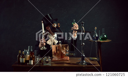 Thoughtful plague doctor in vintage laboratory surrounded by old-fashioned medical tools and glassware against dark mystery background. 121060725
