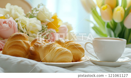 A cozy breakfast in bed with croissants and coffee, surrounded by fresh flowers and morning light 121061127
