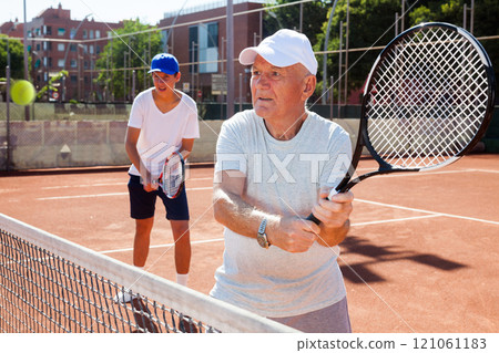 Grandfather and grandson playing tennis court 121061183