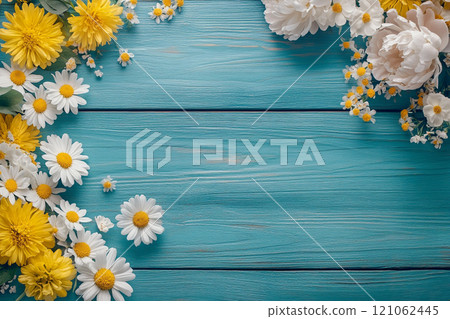 A old wooden plank background with a variety of yellow and white flowers, including daisies on the sides.  121062445