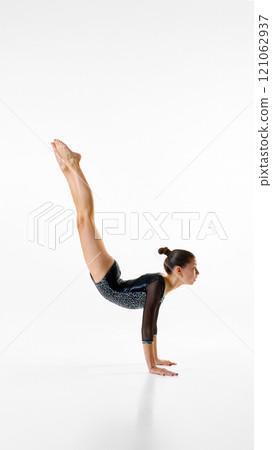 Female, elegant athlete enhances flexibility and movement precision in intense session against white studio background. Copy space. Female, elegant athlete enhances flexibility and movement precision in intense session against white studio background. Copy space. 121062937