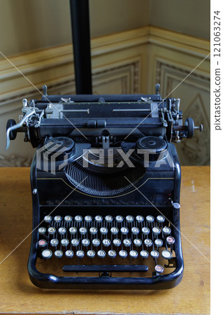 An old fashioned typewriter sits on a wooden table 121063274