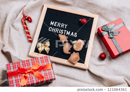 Christmas flatley with a black letter board, with cookies, Christmas tree decorations and gift boxes, on a linen background 121064361