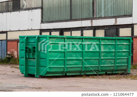 Green trash container standsnear concrete wall Green trash container standsnear concrete wall 121064477