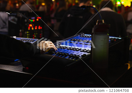 Hand of a sound engineer working at a mixing console in dark studio Hand of a sound engineer working at a mixing console in dark studio 121064708