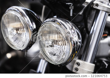 Round front headlights of a shiny black road motorcycle, close up Round front headlights of a shiny black road motorcycle, close up 121064753