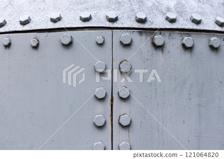 Light gray steel wall with bolts, metal parts connection, close-up 121064820