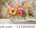 Pretty flowers in vivid colors arranged in a clear glass or acrylic square vase 121064844