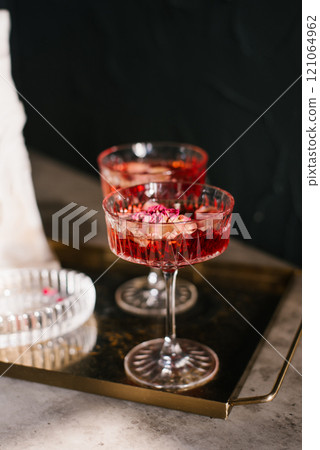 Two glasses of red wine with rose petals in them on a tray. Scene is elegant and sophisticated Two glasses of red wine with rose petals in them on a tray. Scene is elegant and sophisticated 121064962