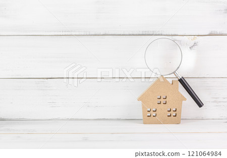 Wooden House with Magnifying Glass on White Wooden Background Representing Real Estate Inspection 121064984