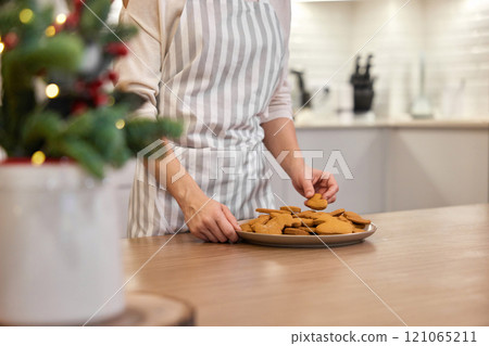 woman holding plate of delicious gingerbread cookies at home, Christmas time woman holding plate of delicious gingerbread cookies at home, Christmas time 121065211