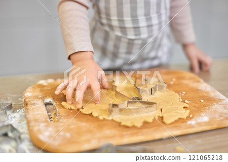 hands of child cutting gingerbread cookies with a cookie cutter in kitchen. festive gingerbread cookies hands of child cutting gingerbread cookies with a cookie cutter in kitchen. festive gingerbread cookies 121065218