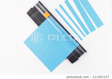 demonstrates the use of a paper trimmer, which is a common tool for precise cutting in crafting, 121065257