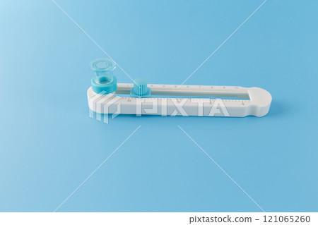 The circle cutter tool with a sliding mechanism with measurements in centimeters, for precise cutting of circles of different sizes. blue background, 121065260