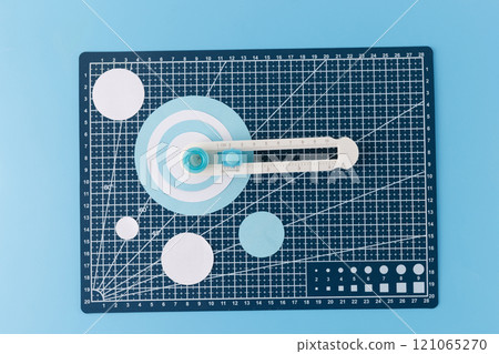 Paper circle cutter tool with blue cutouts on a white background. Close-up. Arts and crafts tool concept for design and print. trimmer 121065270