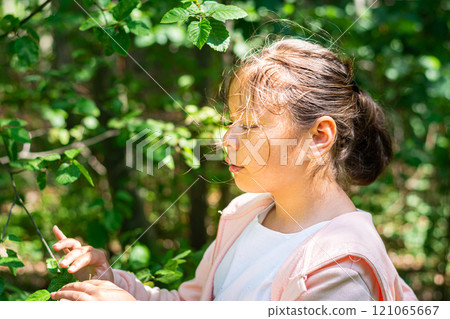 A young school girl in white and pink standing in lush green foliage A young school girl in white and pink standing in lush green foliage 121065667