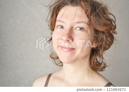 Caucasian female adult with bandages on forehead smiling against neutral 121065672