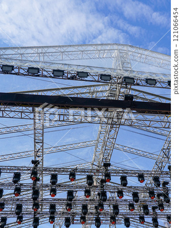 Fragment of metal trusses and lighting elements of a large outdoor concert stage Fragment of metal trusses and lighting elements of a large outdoor concert stage 121066454