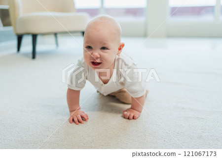 Happy baby. Cute little newborn girl with smiling face crawling on floor in bedroom. Infant baby resting playing in living room indoor at home. Motherhood happy child childcare concept Happy baby. Cute little newborn girl with smiling face crawling on floor in bedroom. Infant baby resting playing in living room indoor at home. Motherhood happy child childcare concept 121067173