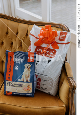 There are two bags of dog food resting on a chair nearby There are two bags of dog food resting on a chair nearby 121067483