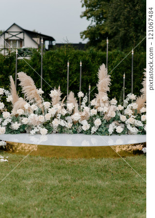 A display of white flowers and pampas grass sits on a green field A display of white flowers and pampas grass sits on a green field 121067484