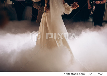 A bride and groom dance in the fog at their wedding reception A bride and groom dance in the fog at their wedding reception 121067523