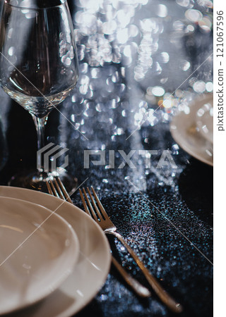 On the table, there are plates, forks, knives, and wine glasses 121067596