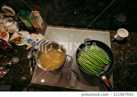 Asparagus cooks in a frying pan beside boiling water Asparagus cooks in a frying pan beside boiling water 121067692
