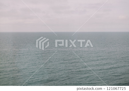 A large expansive body of water with a cloudy sky in the background 121067725