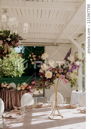 There exists a long table that has a beautiful vase of flowers sitting on it There exists a long table that has a beautiful vase of flowers sitting on it 121067798