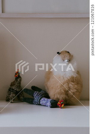 A stuffed animal sits on a white shelf by a Christmas tree A stuffed animal sits on a white shelf by a Christmas tree 121067816