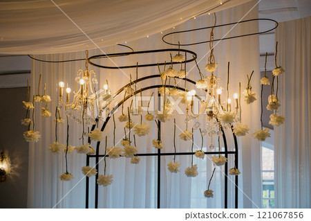 A chandelier decorated with flowers and candles hangs elegantly 121067856