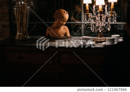 In a dark room, there is a statue of a child positioned on a table 121067866