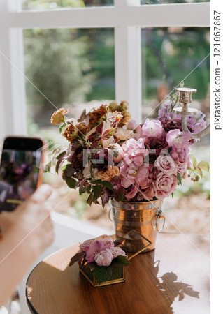 A person is photographing a vase of flowers on a table A person is photographing a vase of flowers on a table 121067867