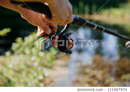 A person is firmly holding a fishing rod in their hand right now 121067874